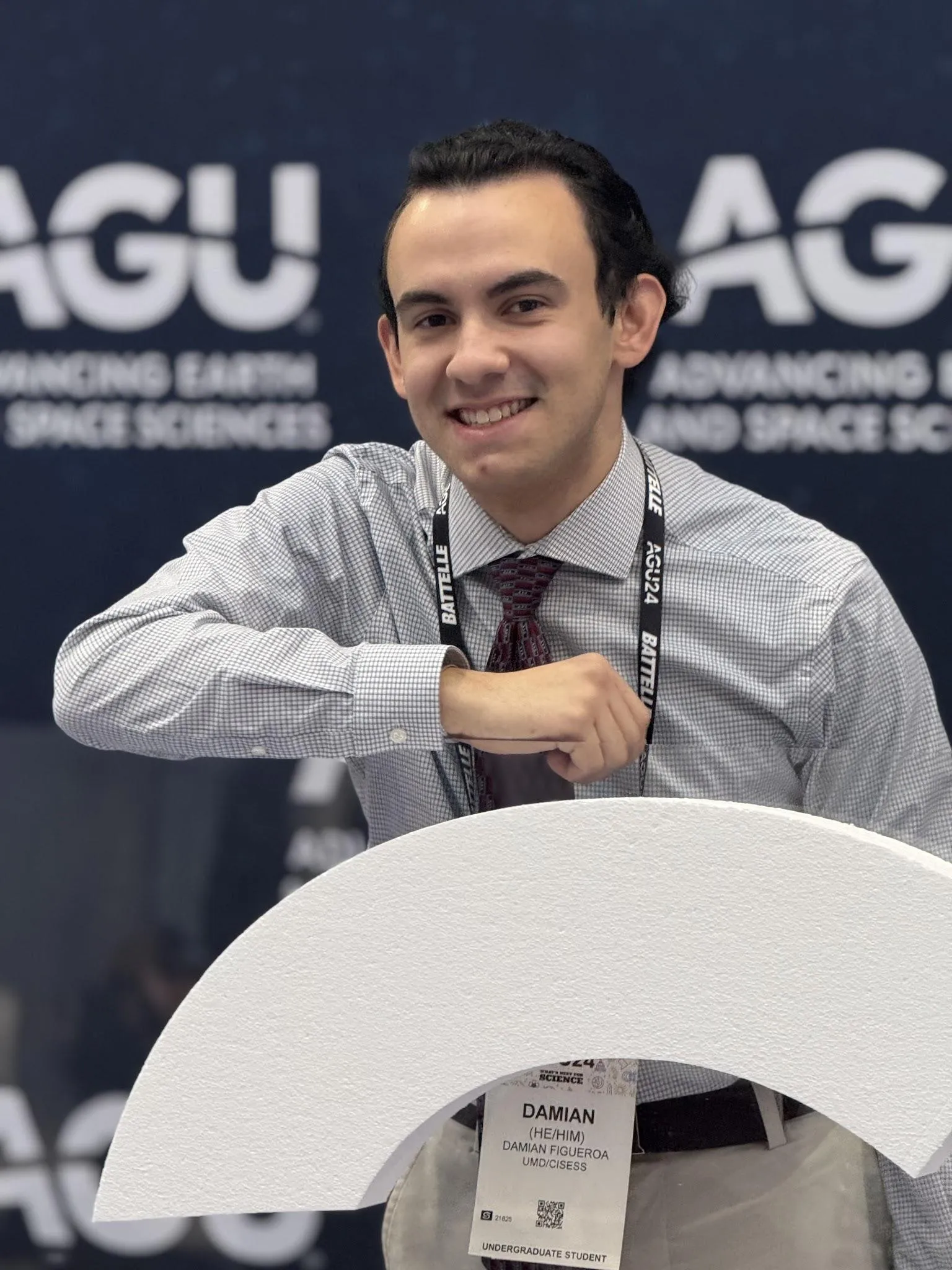 Close up of D.J. at the AGU 2024 sign.